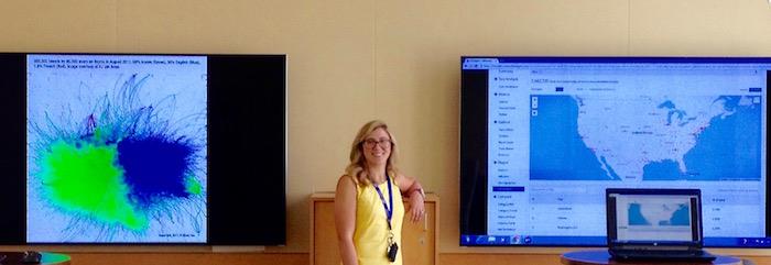 Collaboratory Director Stephanie Tulley stands between two huge 85-inch 4K monitors